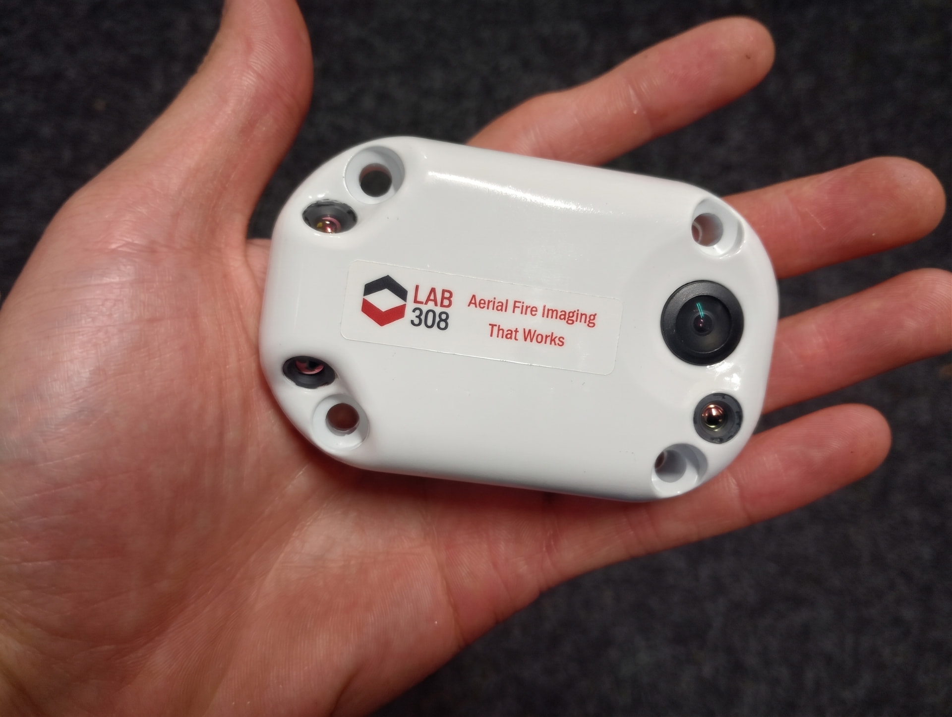 Lab 308 miniARINC Mapper resting in an open palm, showing its compact white housing, LAB 308 label, mounting holes and camera lenses